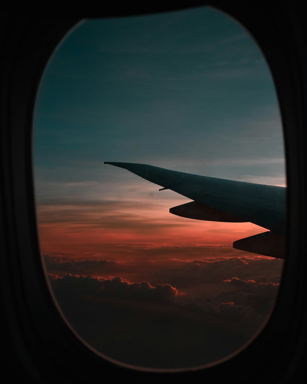 An aircraft wing seen from the cabin window at sunset