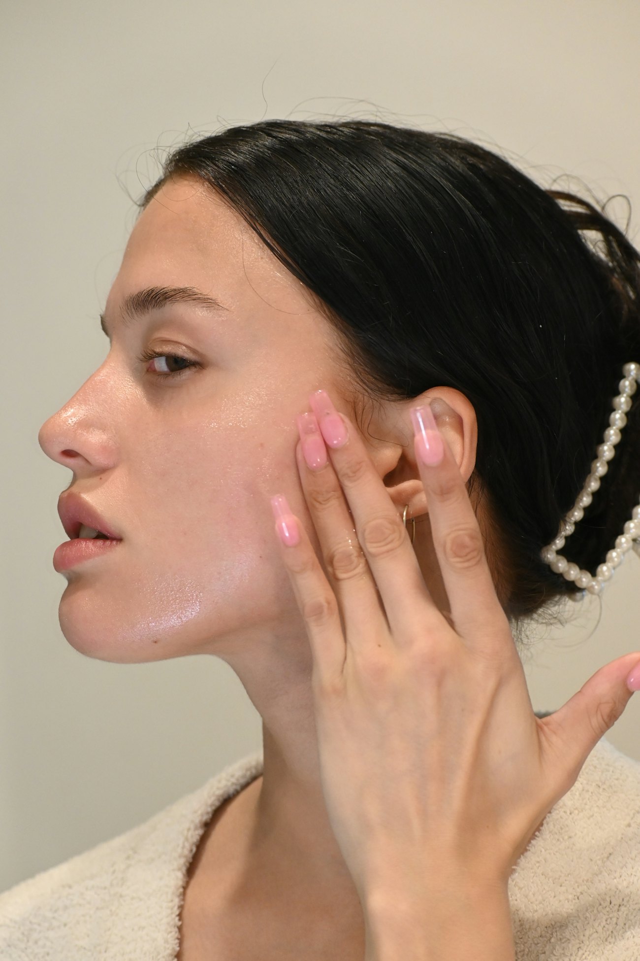 A woman in profile touching her cheek