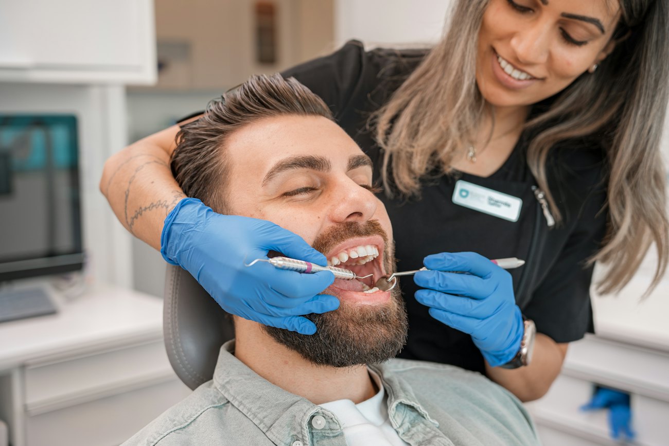 A dentist examines a smiling patient's teeth